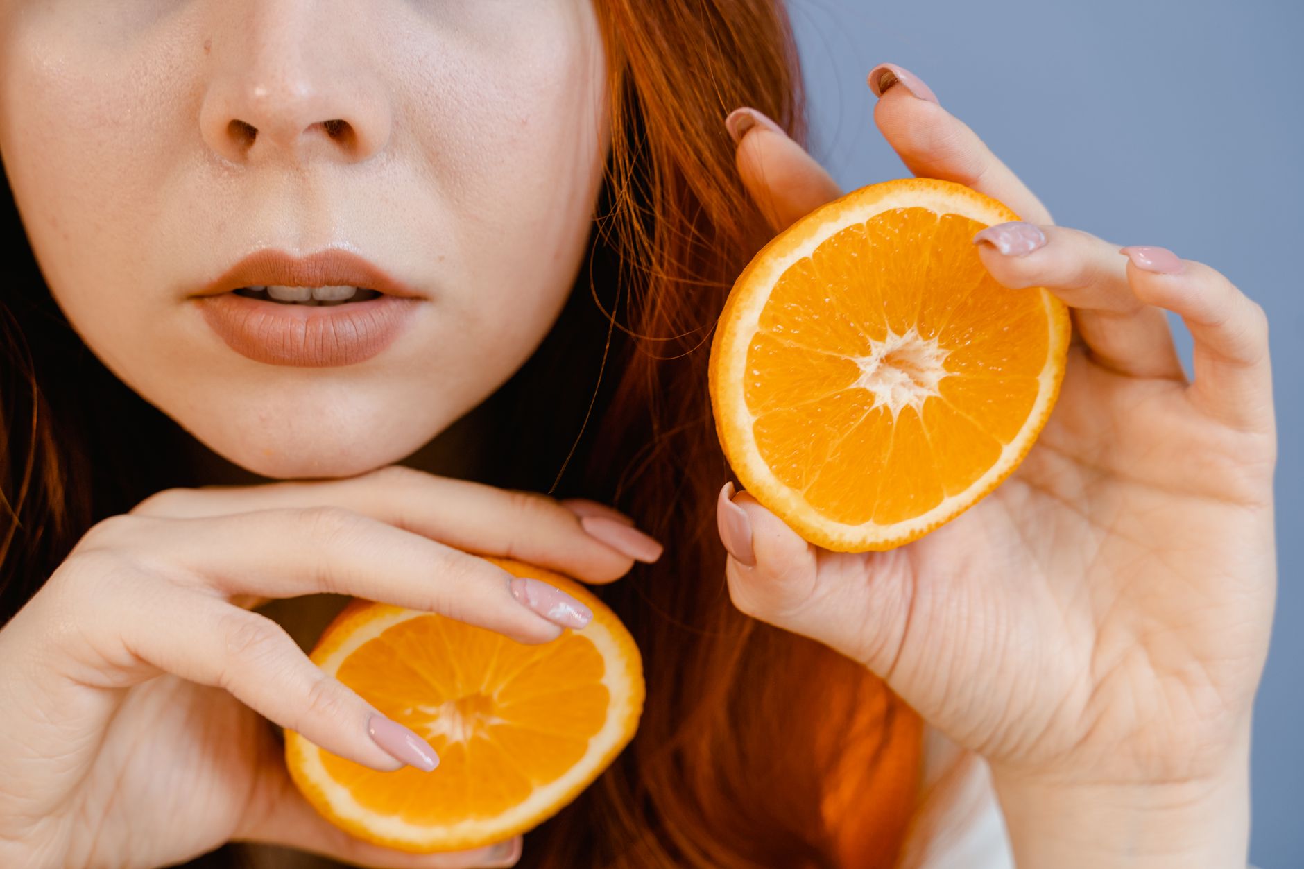 woman holding slices of orange fruit